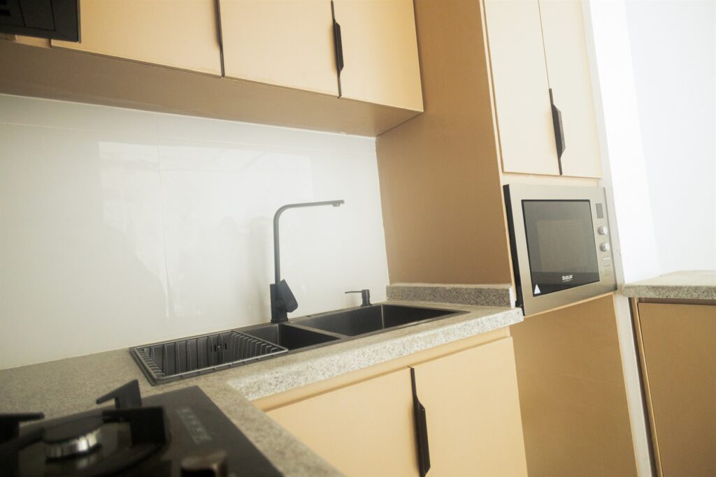 Brum Height 4: Kitchen sink and cabinetry beside a built-in microwave